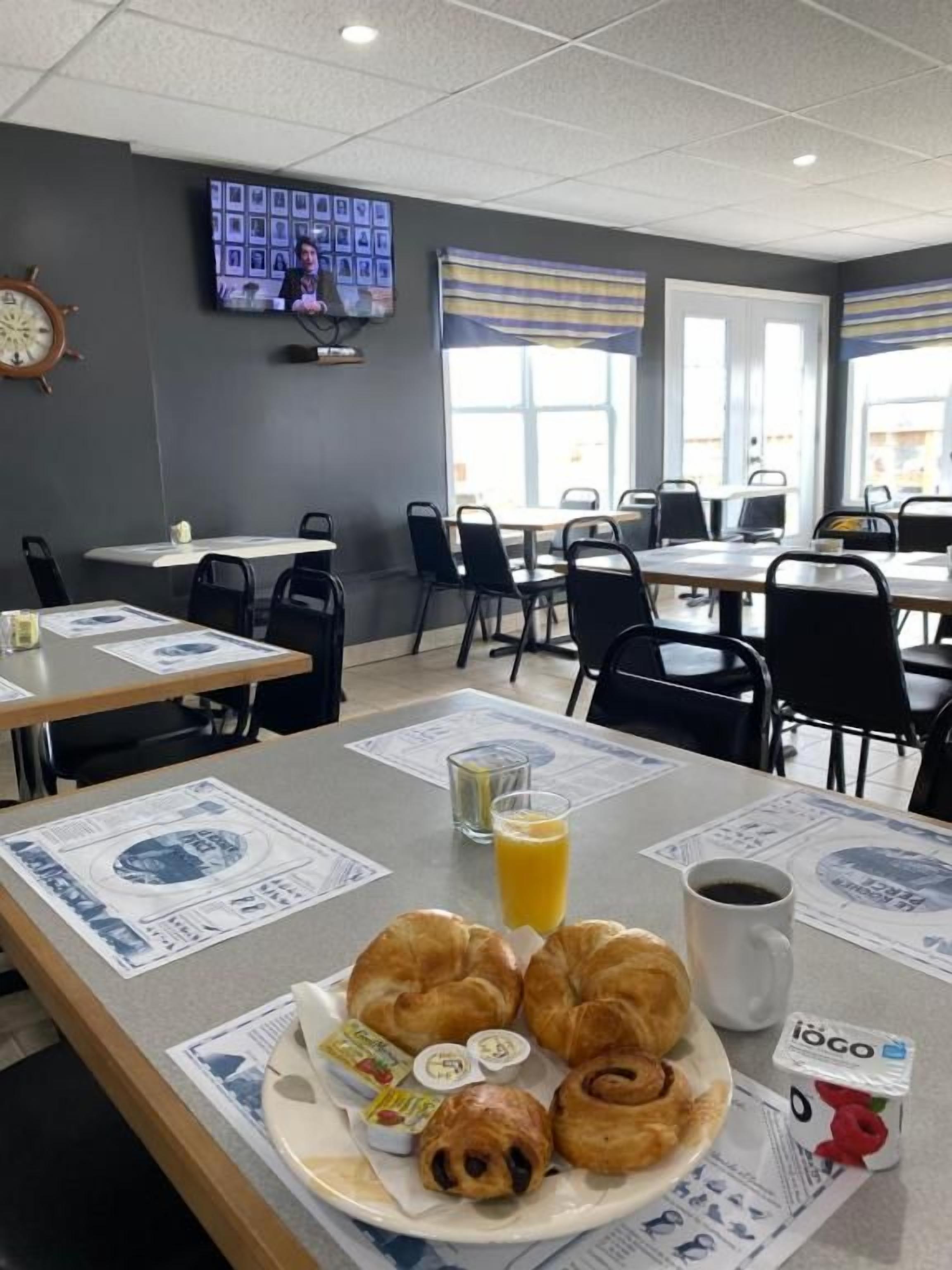 A breakfast setting with croissants, juice, and coffee, and a television on the wall.