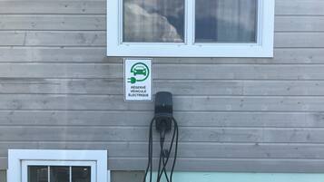 Un bâtiment doté d’une borne de recharge pour véhicules électriques, d’une fenêtre et d’une petite porte.