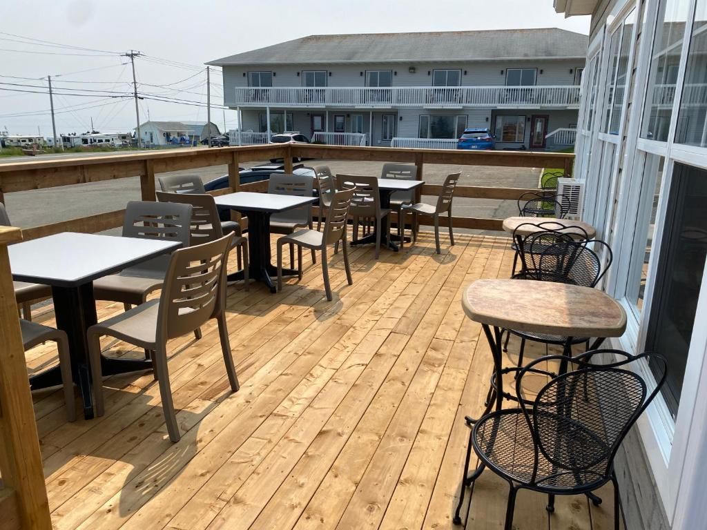 Un patio al aire libre con suelo de madera, mesas y sillas.