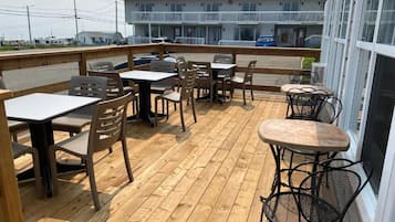 Un patio al aire libre con suelo de madera, mesas y sillas.