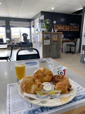 A breakfast setting with croissants, a glass of orange juice, and a cup of coffee on a table. - Hotel Motel Panorama de Perce (Perce)