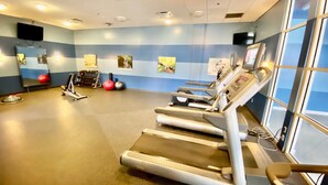 Un gimnasio con cintas de correr, pelotas de ejercicio y pesas.
