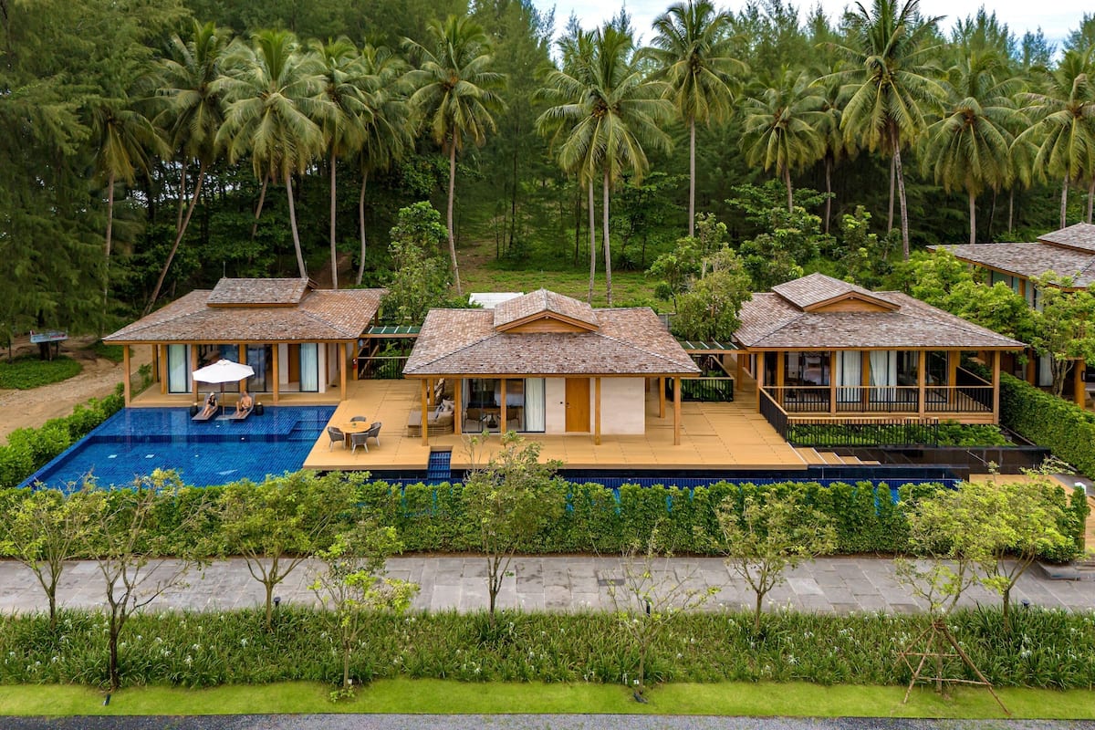 Ein Resort mit mehreren bungalowsartigen Gebäuden, einem Swimmingpool und üppiger tropischer Landschaft.
