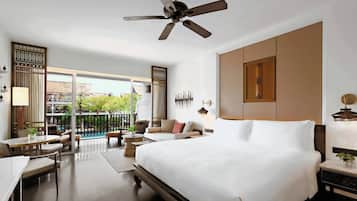 Een hotelkamer met een groot bed, een plafondventilator, een balkon met buitenmeubilair en uitzicht op de stad.