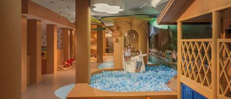A children's play area with a ball pit, slides, and soft seating.