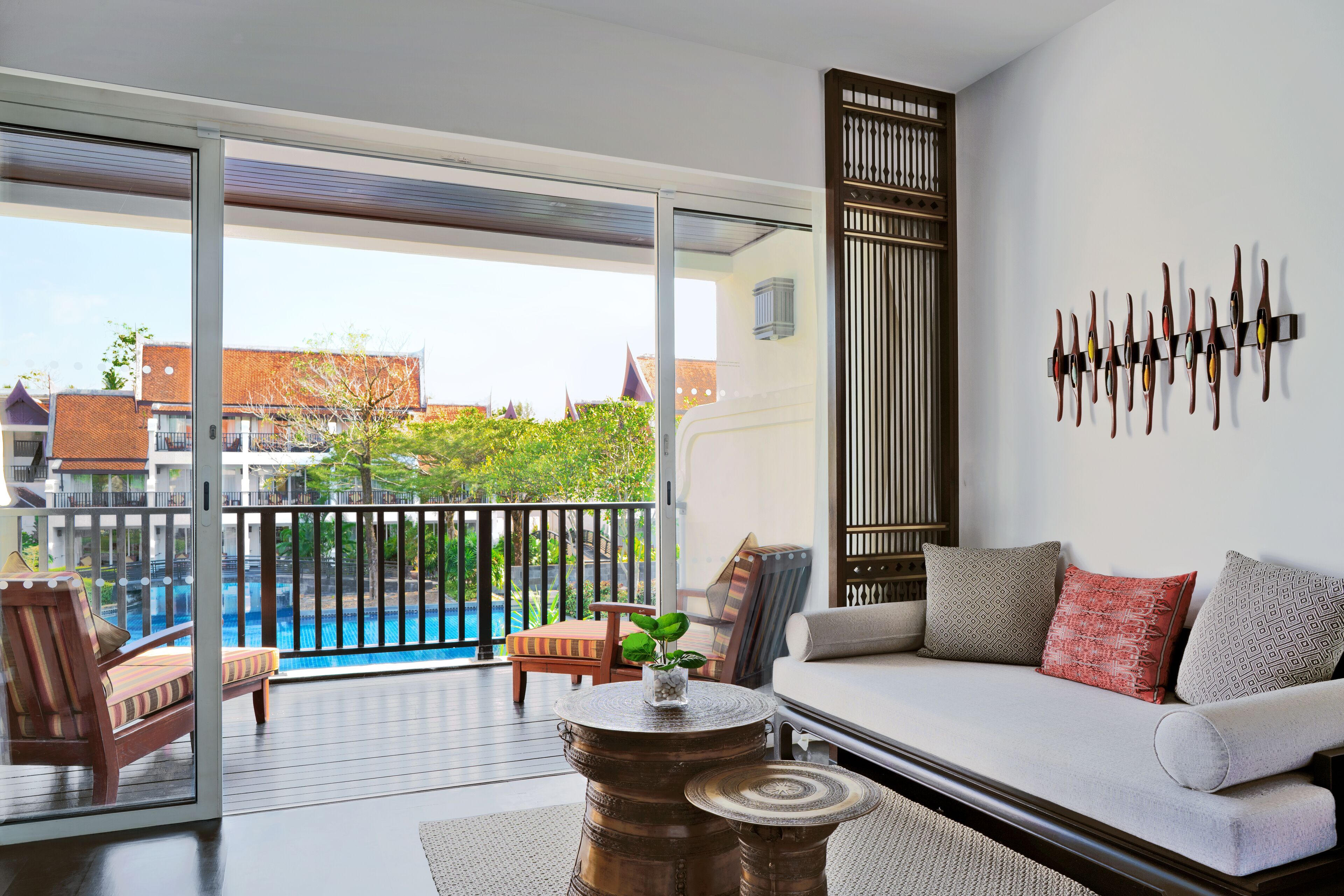 A modern living room with a sofa, a coffee table, and a view of a swimming pool.