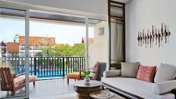 A modern living room with a sofa, a coffee table, and a view of a swimming pool.