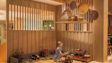 A room with wooden paneling, a child playing with toys, and various baskets and containers on the floor.