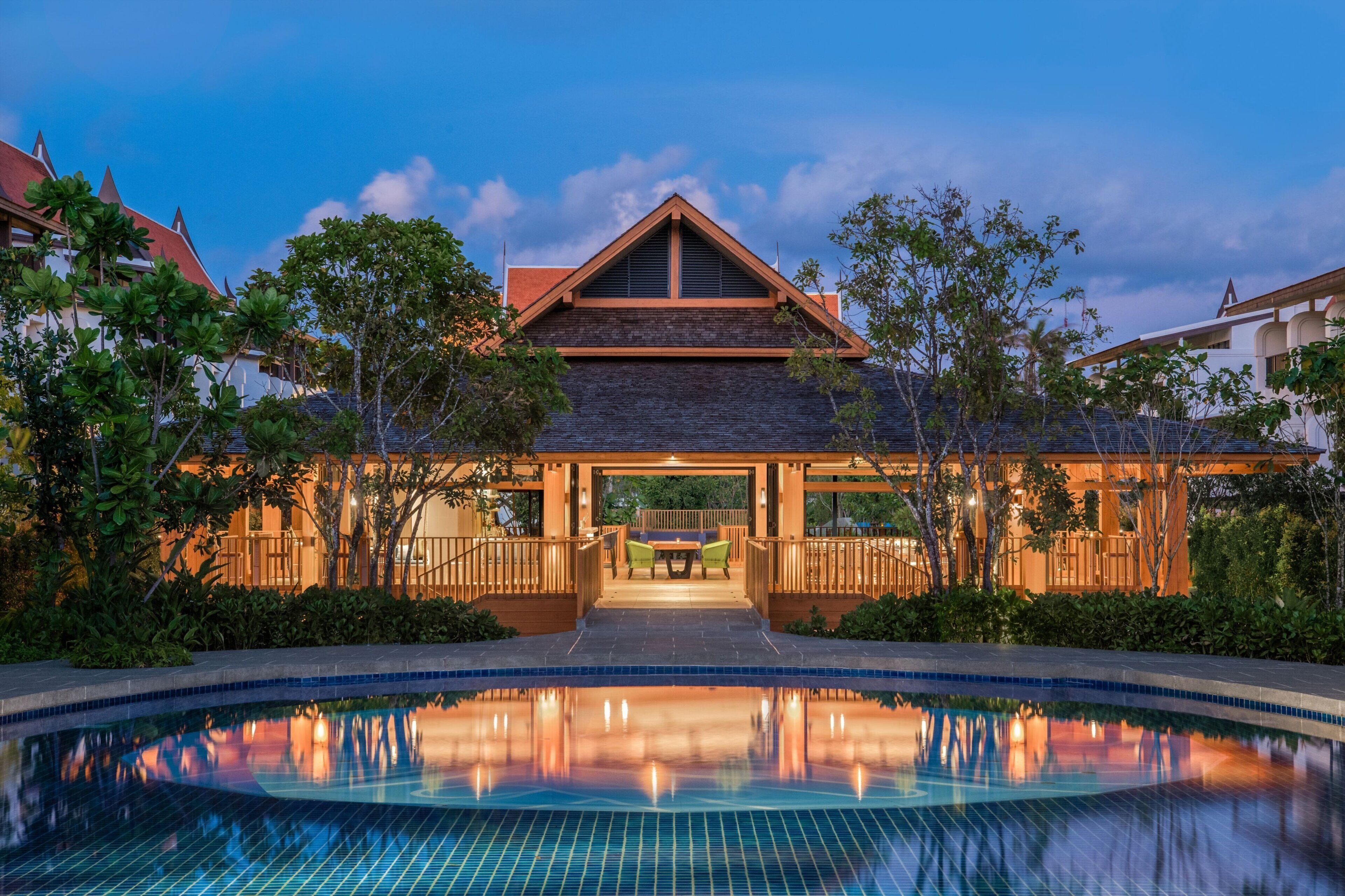 A resort with a swimming pool, a covered patio, and a view of the surrounding landscape.