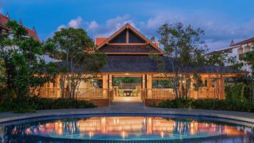 A resort with a swimming pool, a covered patio, and a view of the surrounding landscape.