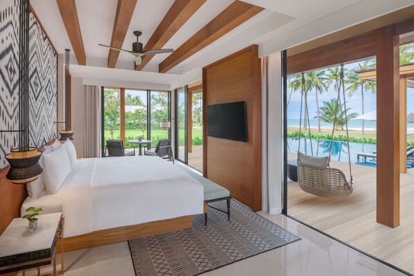 Una habitación de hotel moderna con una cama grande, televisión y vistas a la playa.