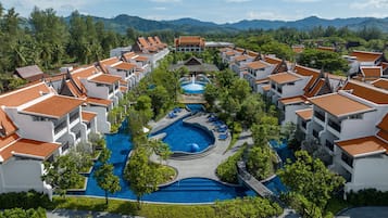 A resort with multiple buildings, a central swimming pool, and surrounding greenery.