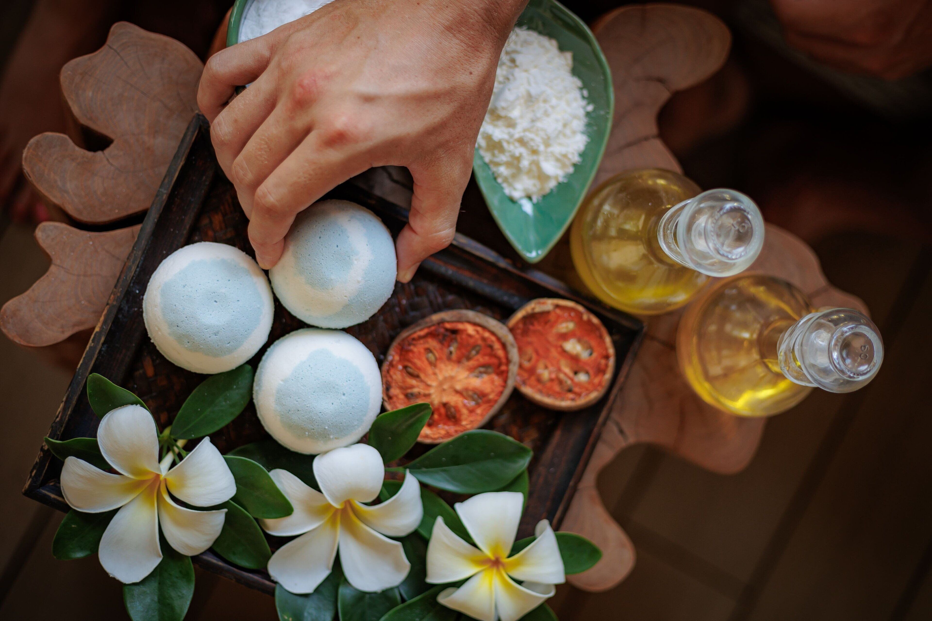 A tray with white flowers, a bowl of white powder, and two bottles of yellow liquid.