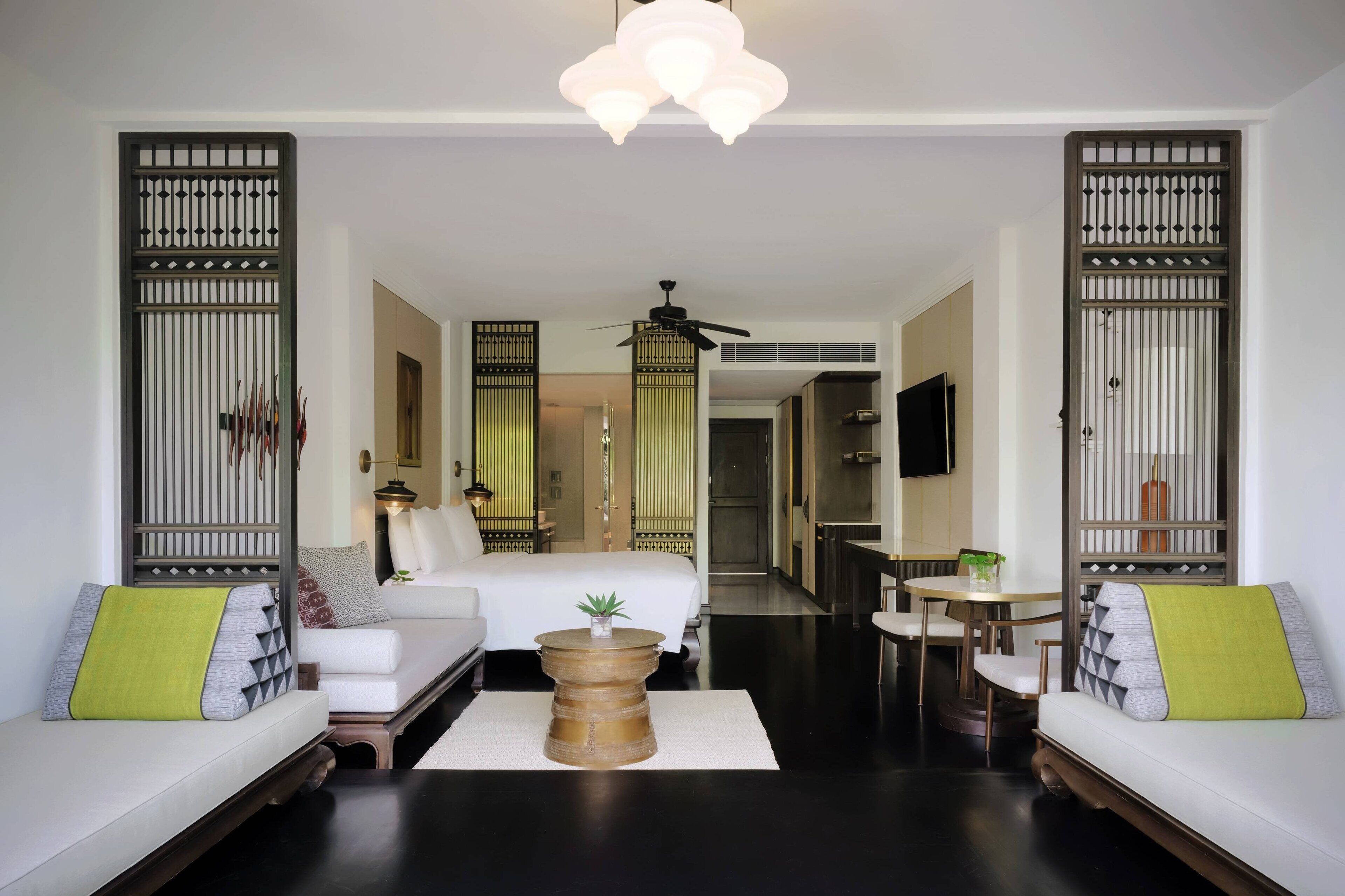 A modern hotel room with a sofa, a round coffee table, and a TV.