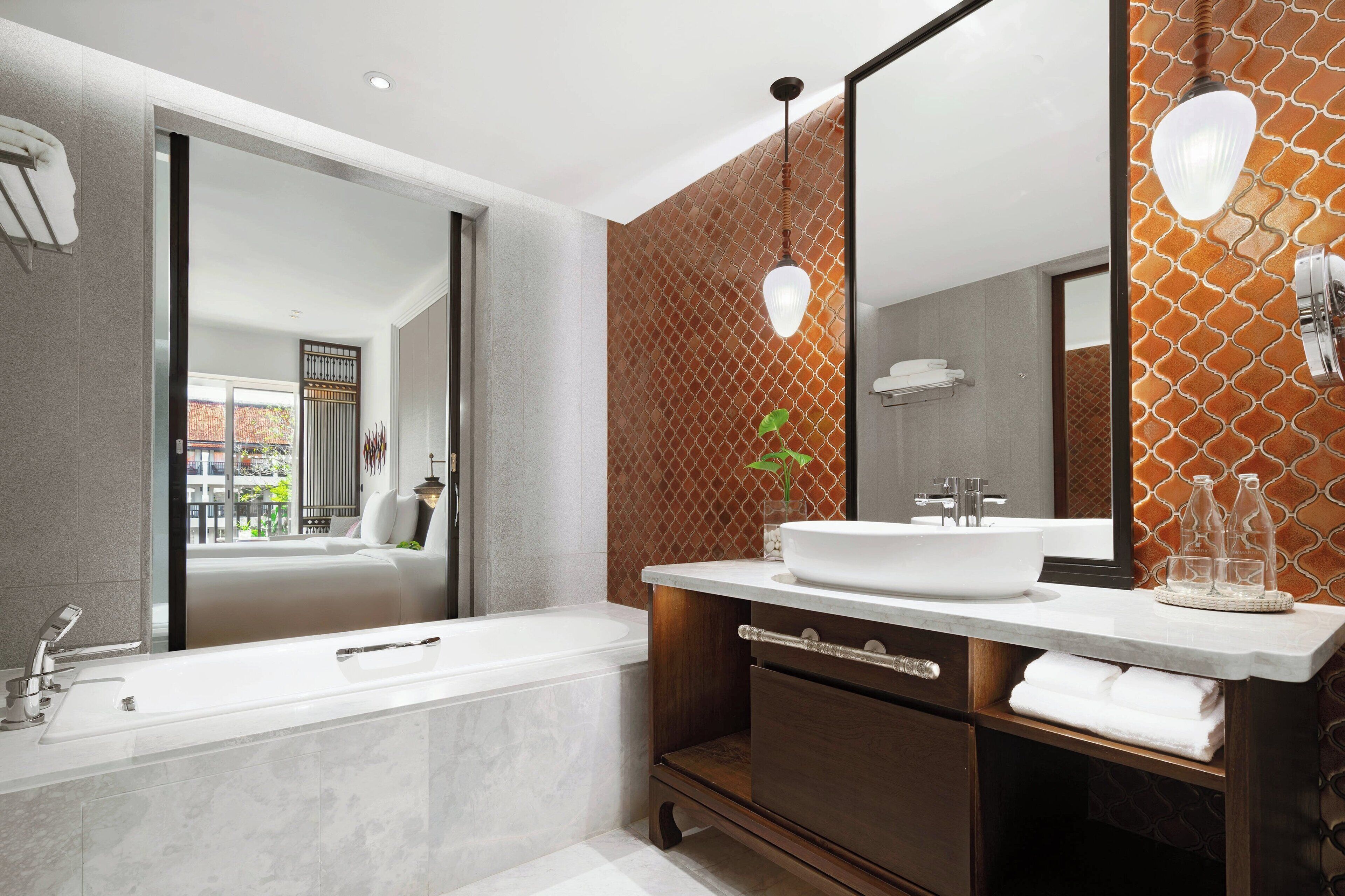 A modern bathroom with a large mirror, a bathtub, and a vanity with a sink.