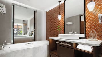 A modern bathroom with a large mirror, a bathtub, and a vanity with a sink.