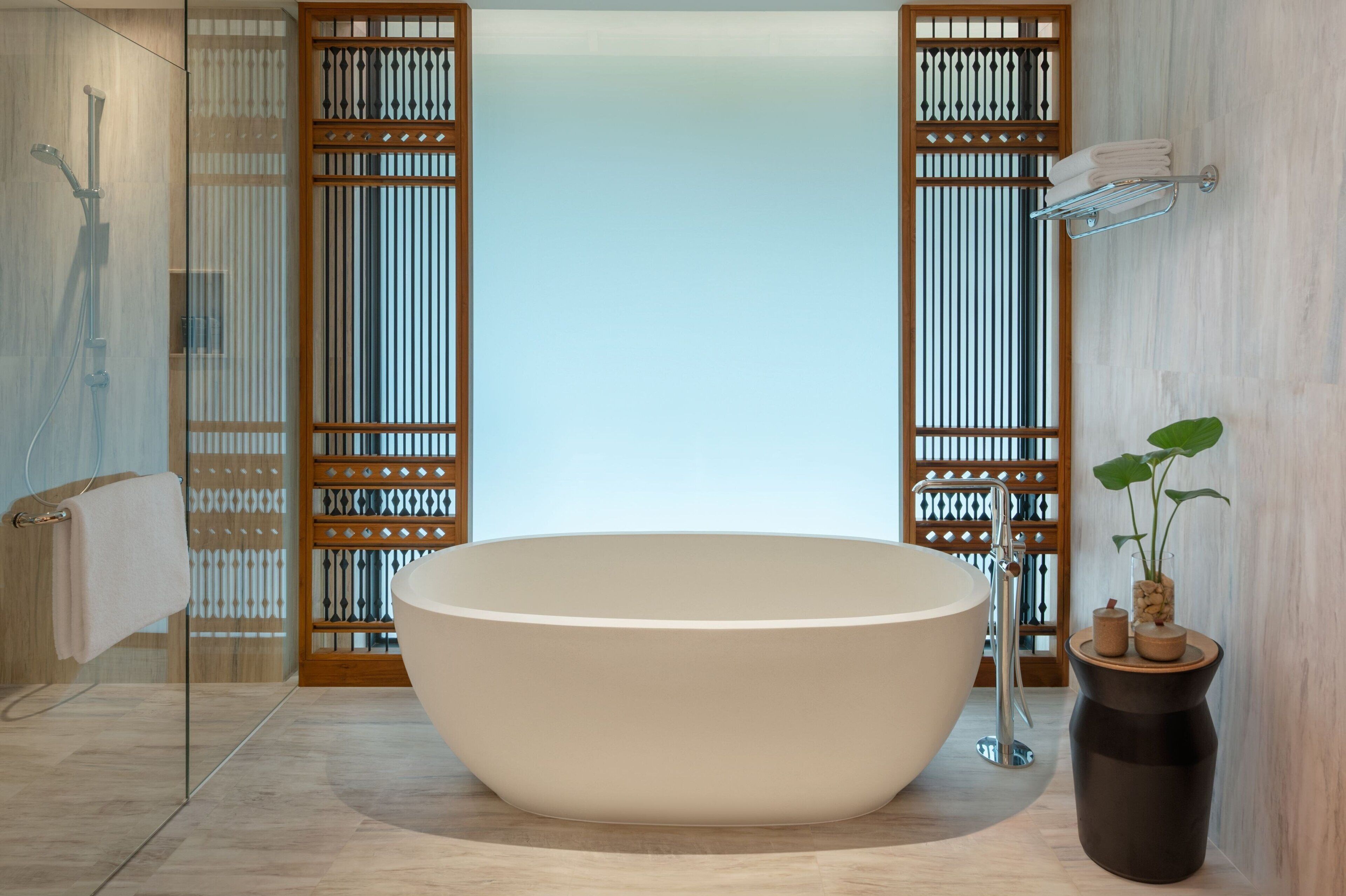 Une salle de bain moderne avec une baignoire sur pieds, une douche à parois de verre et une cloison en bois avec des lattes verticales.