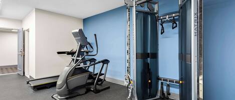 A gym with a treadmill, a weight machine, and a pull-up bar.