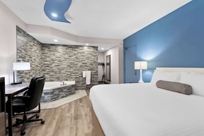 A modern hotel room with a large bed, a desk with a chair, a bathroom with a stone backsplash, and a blue accent wall. - SureStay Plus by Best Western Windsor (Windsor)