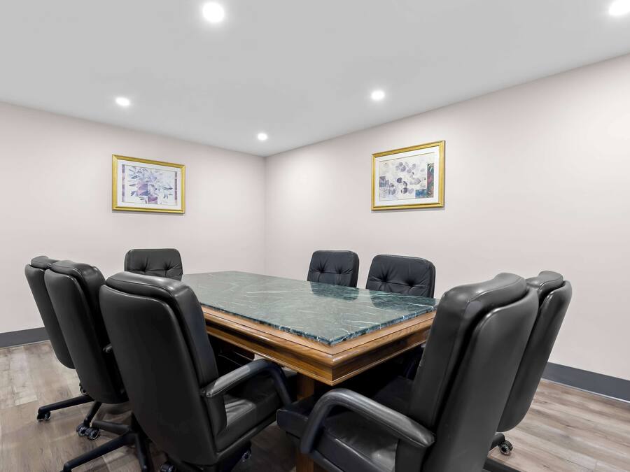 Un salón de conferencias con una mesa de vidrio y sillas de cuero negro.
