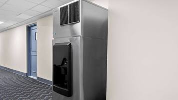 Un mini-bar en acier inoxydable, doté d’un distributeur de boissons, situé dans un couloir d’hôtel.