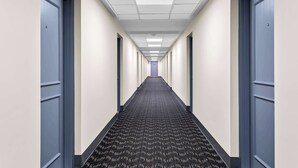 A long, narrow hallway with a patterned carpet, white walls, and blue doors on both sides. - SureStay Plus by Best Western Windsor (Windsor)