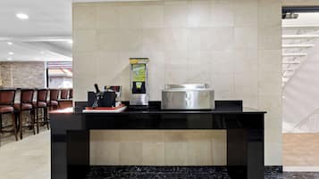 A reception area with a counter, a coffee machine, and a menu dispenser.