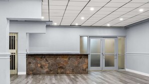 A spacious room with a stone accent wall, a wooden floor, and a glass door with frosted glass panels. - SureStay Plus by Best Western Windsor (Windsor)