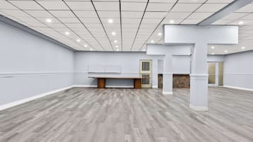Una habitación amplia con suelo de madera, paredes blancas e iluminación empotrada en el techo.