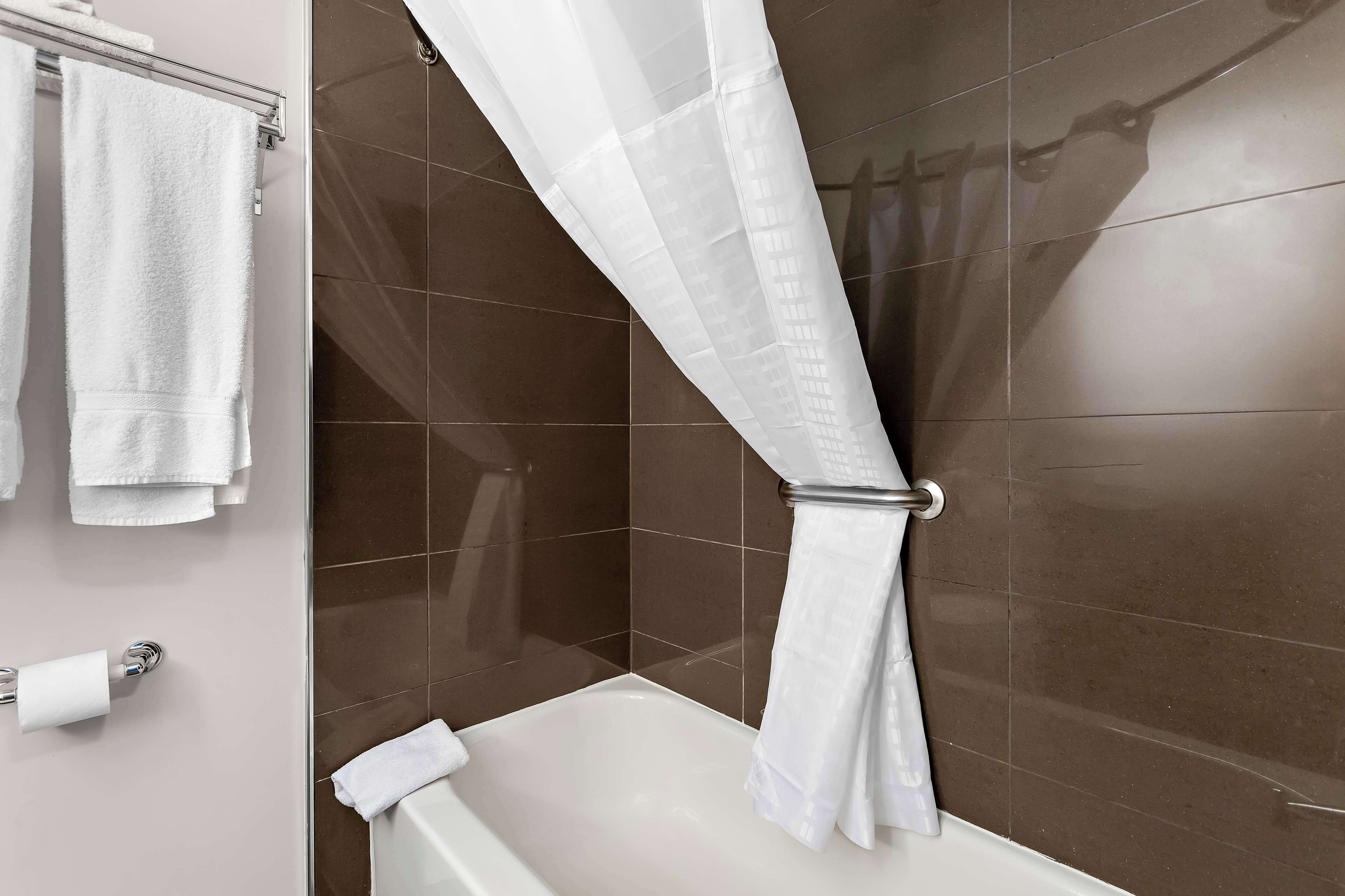 Un baño con bañera, cortina de ducha y un perchero con varias toallas.