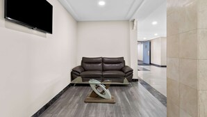 A modern interior with a leather sofa, a glass coffee table, and a flat-screen TV mounted on the wall. - SureStay Plus by Best Western Windsor (Windsor)