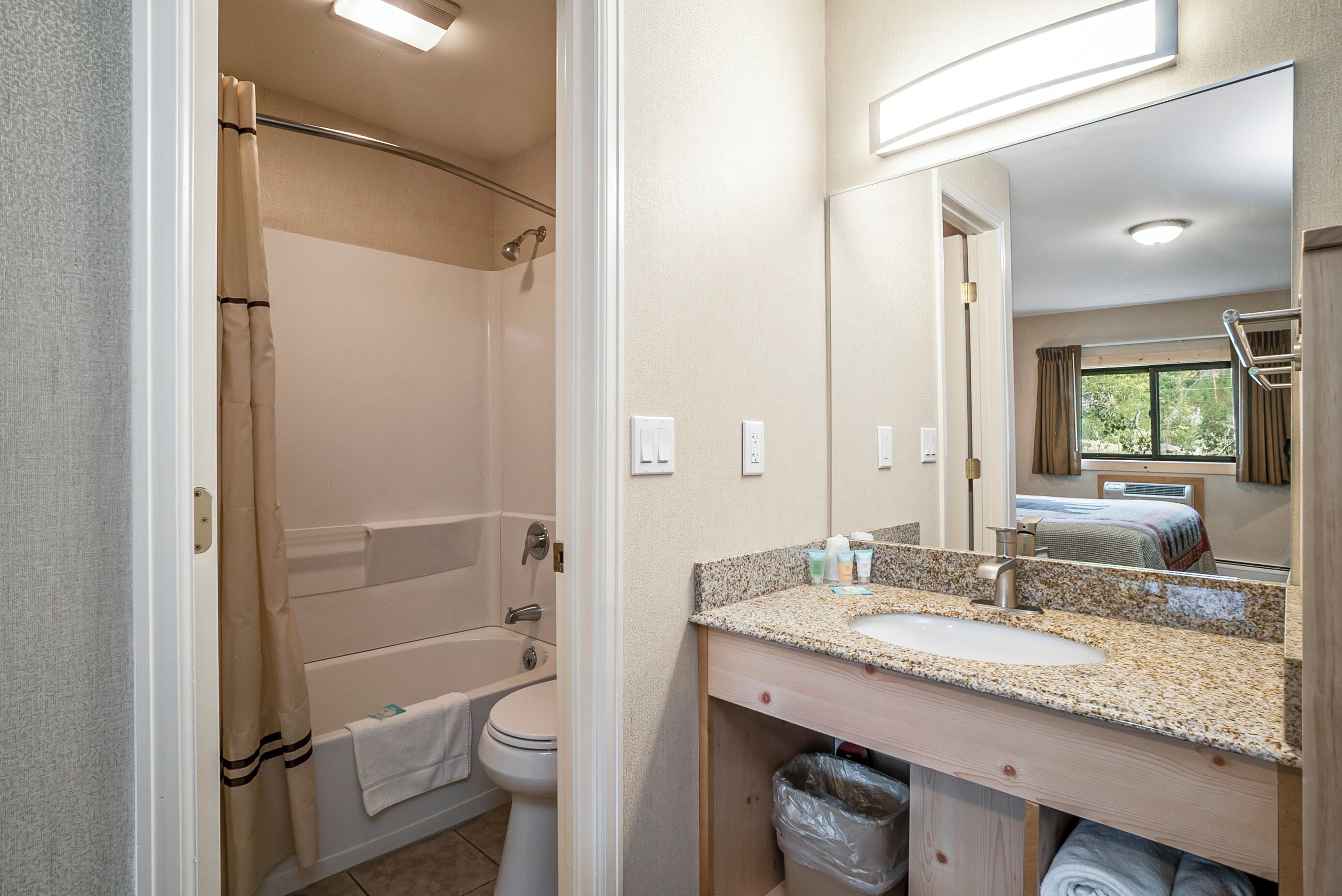 A bathroom with a bathtub, toilet, sink, and a mirror.