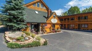 A log cabin-style building with a 'VACANCY' sign, a large American flag, and a statue of a cowboy. - Spirit Lake Lodge (Grand Lake)