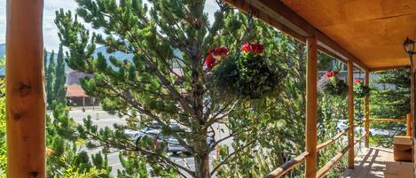 Un balcón de madera con vistas a un estacionamiento y árboles.