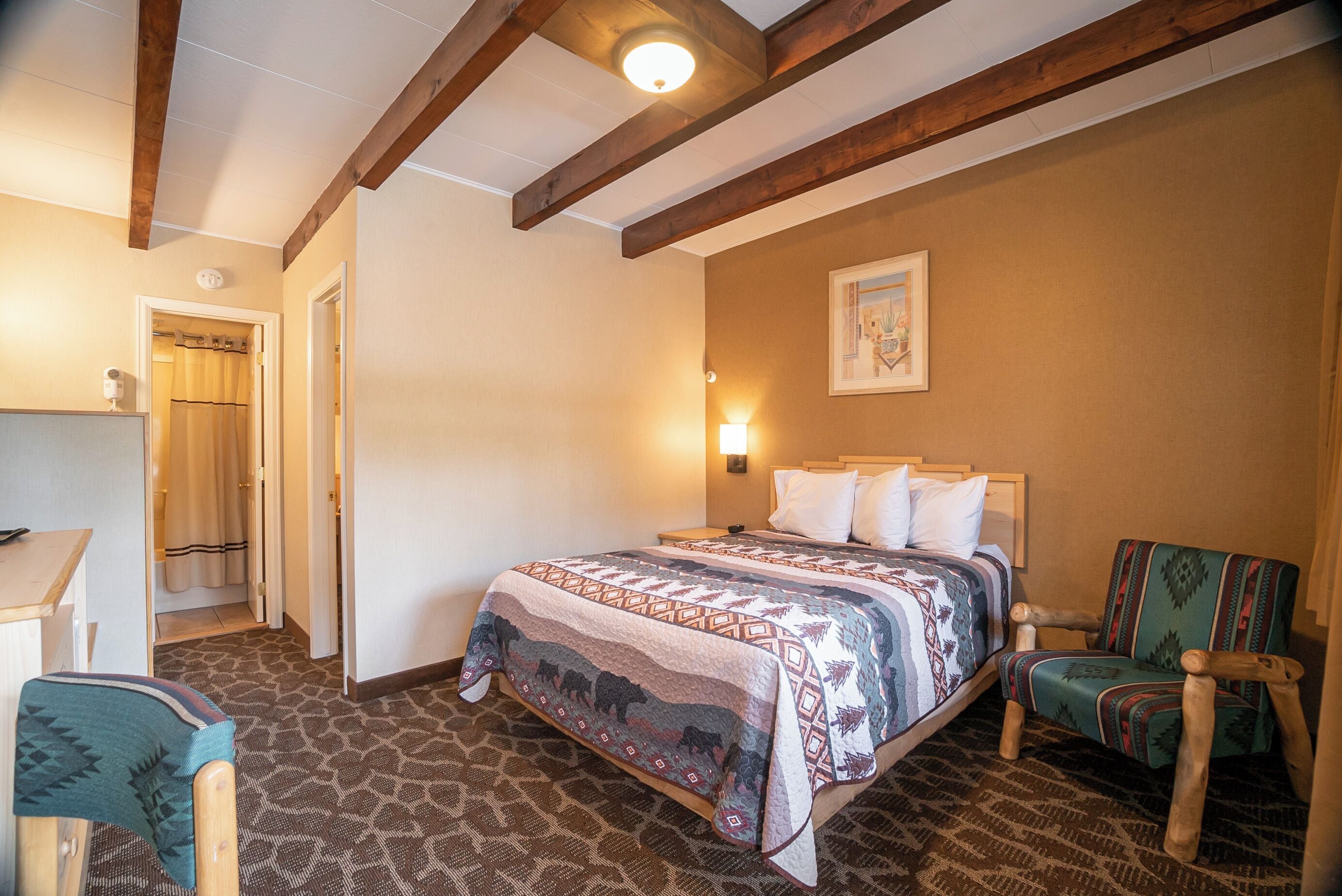 Quarto com cama, cadeira, escrivaninha e porta do banheiro.