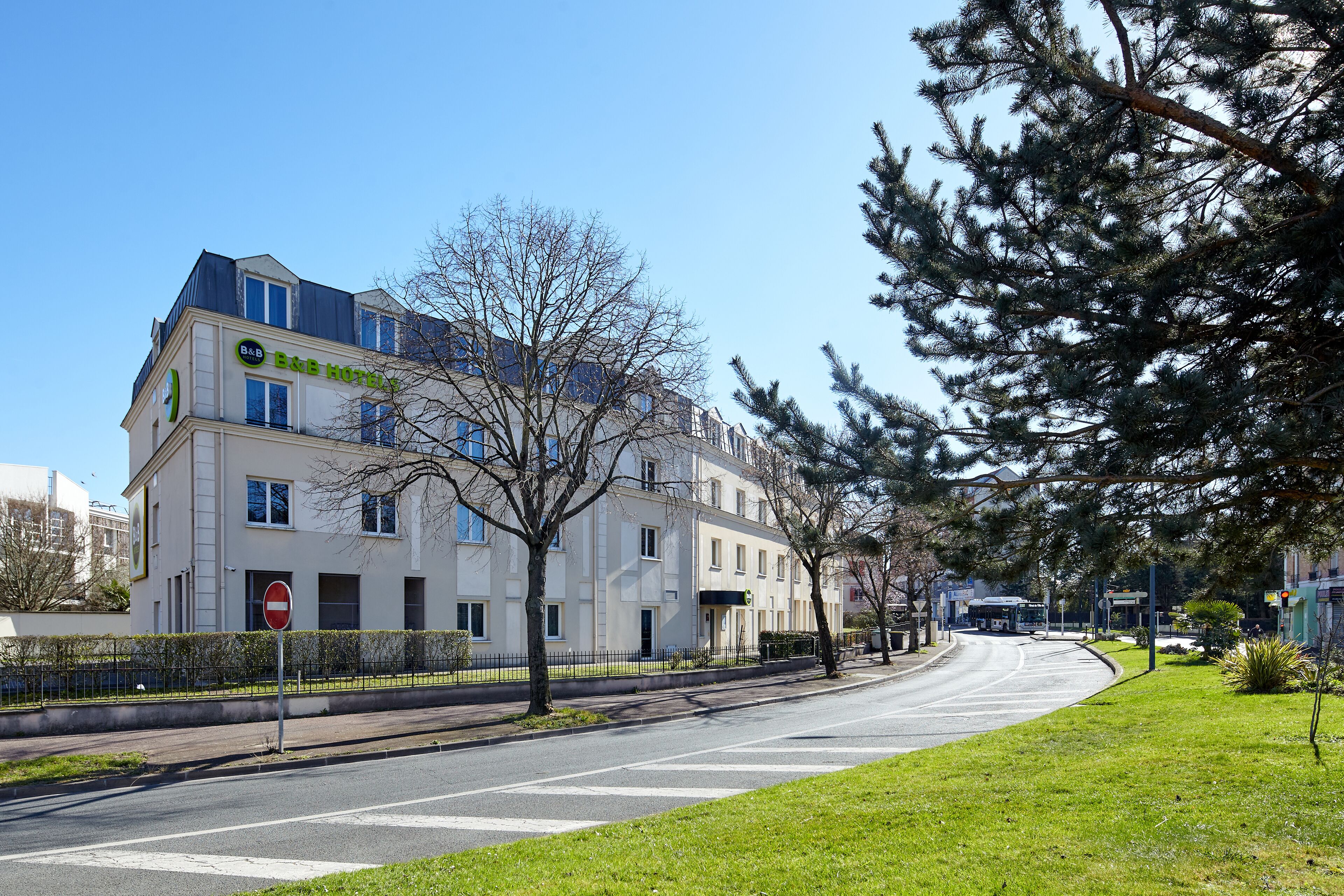 A B&B hotel with a modern design, located on a quiet street with a clear sky.