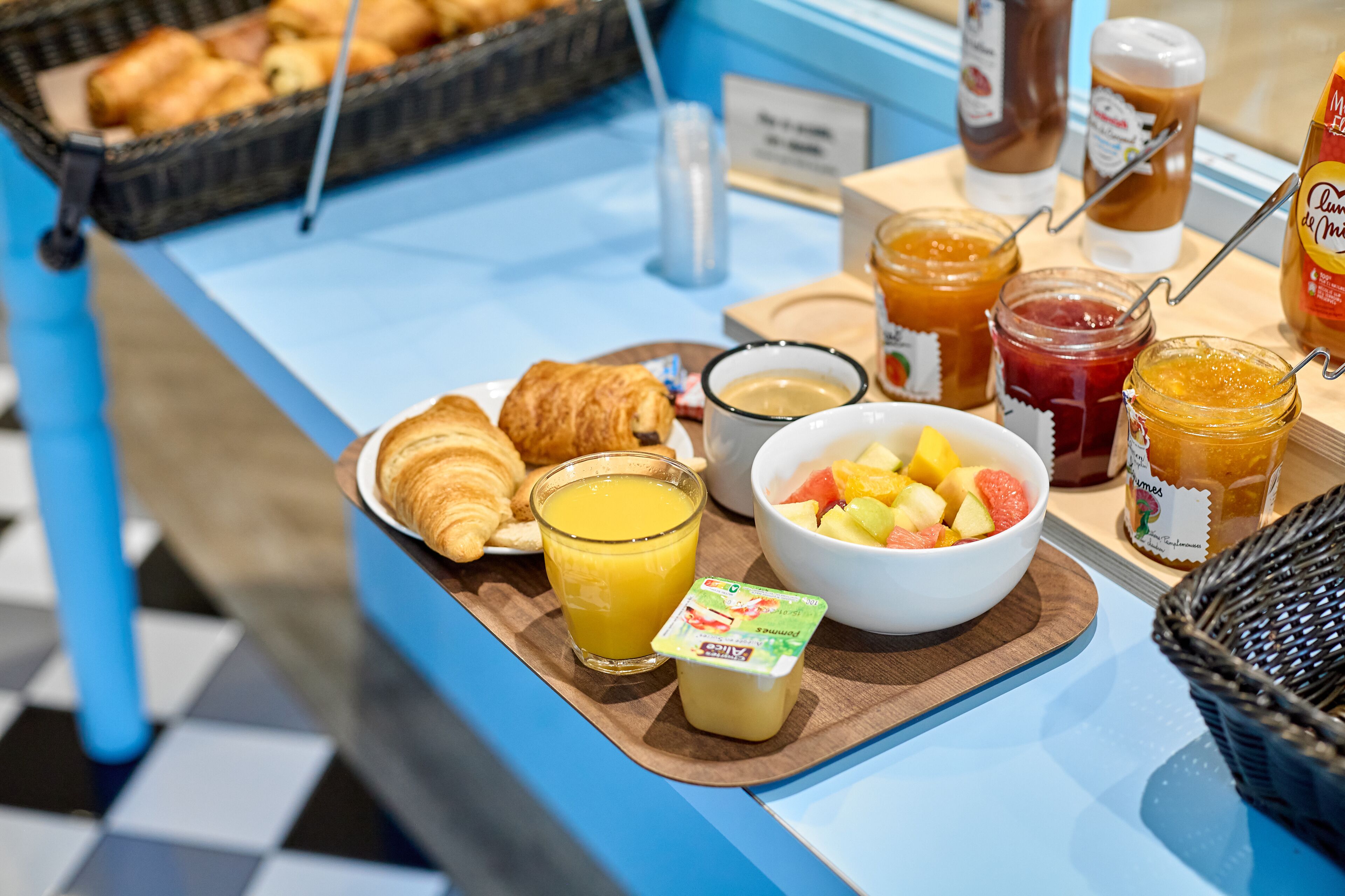 A breakfast buffet with croissants, fruit, juice, and various spreads.