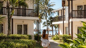 Un resort con un camino que lleva a una zona de piscina, rodeado de palmeras y follaje.
