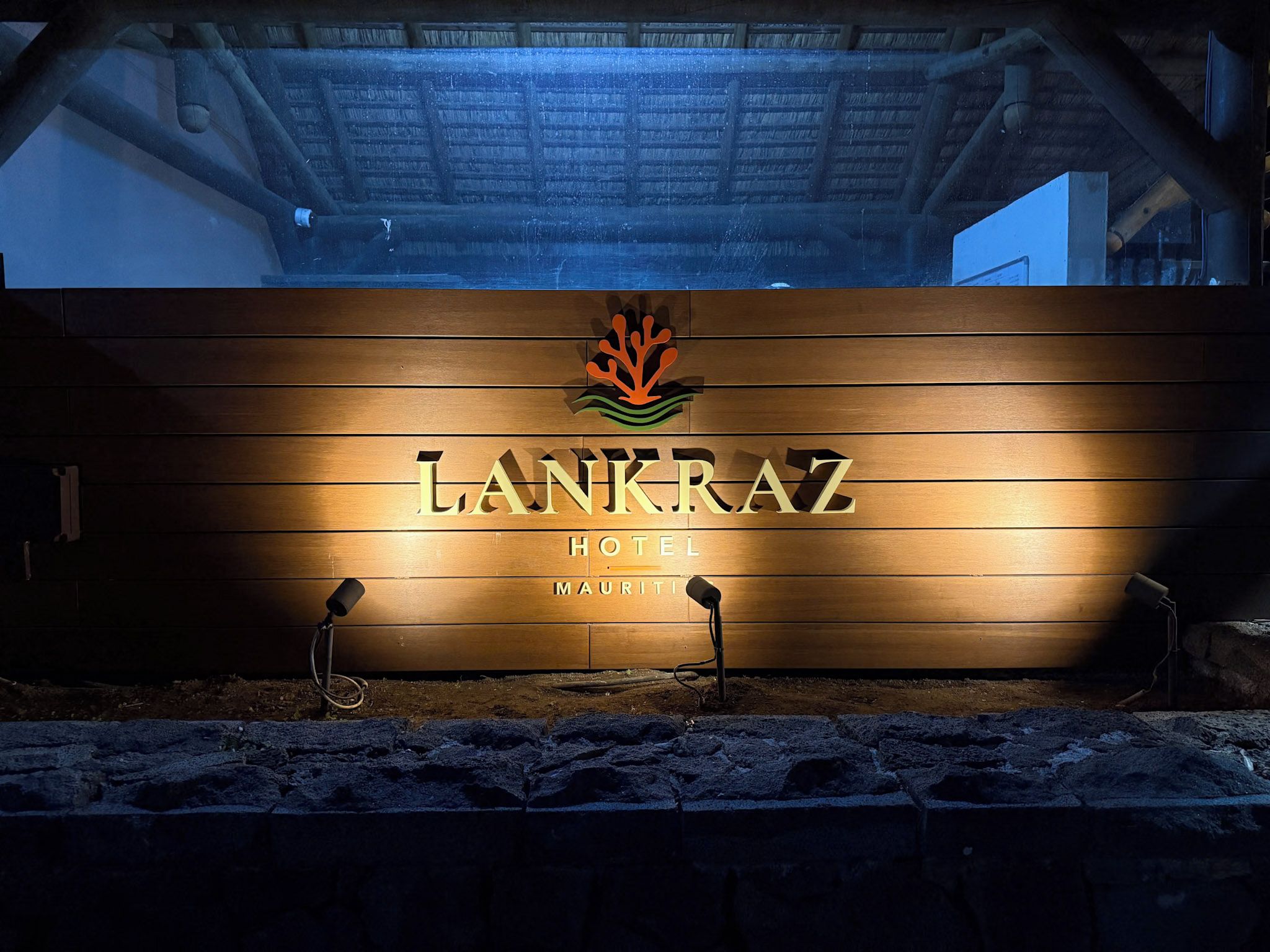 A wooden signboard with the name 'LANKRAZ HOTEL' and a logo above it.