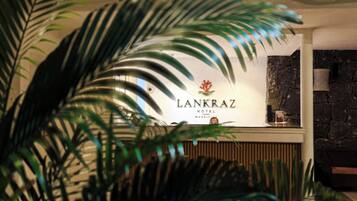 A reception desk with a sign for 'Lankraz Hotel Mauritius' and a stone wall in the background.