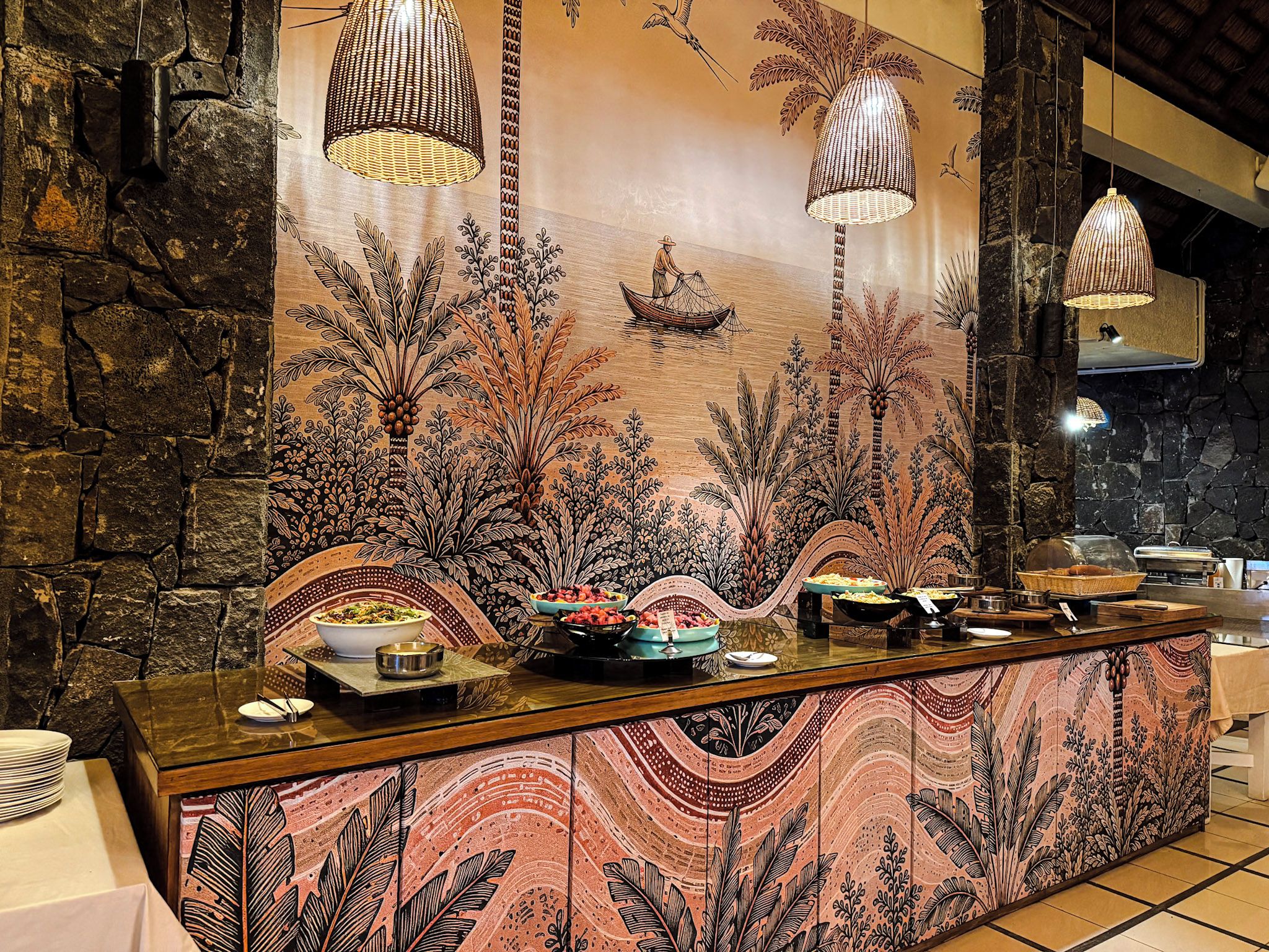 A buffet area with a decorative backdrop, a stone wall, and hanging light fixtures.