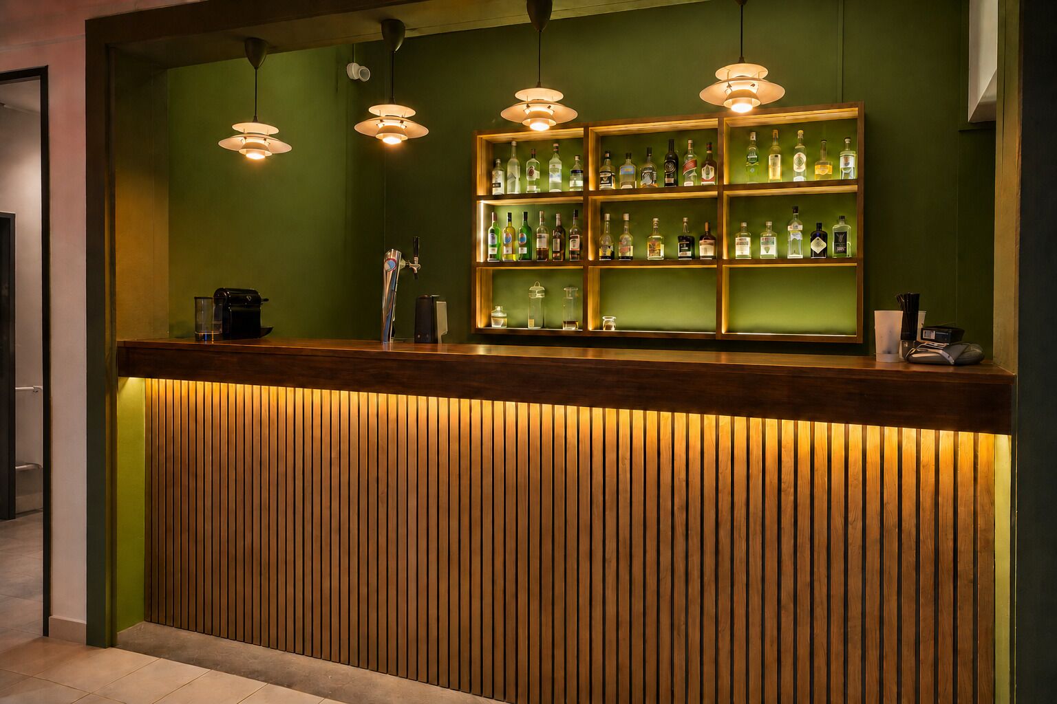 A reception desk with a wooden slat design, overhead pendant lighting, and a glass display case with various bottles.