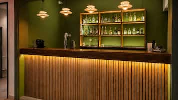 A reception desk with a wooden slat design, overhead pendant lighting, and a glass display case with various bottles.