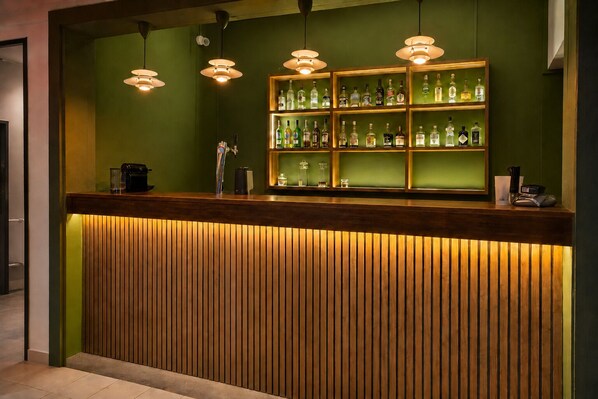 A reception desk with a wooden slat design, overhead pendant lighting, and a glass display case with various bottles. - Lankraz Hotel, Mauritius (Tombeau Bay)