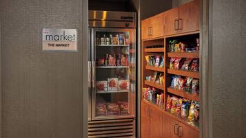 A refrigerated display case with various food items and a wooden cabinet with snacks.