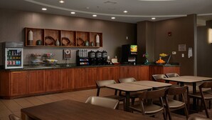 Een hotel eetruimte met houten kasten, een koffieapparaat en een koelkast.