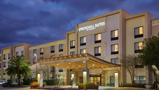 Een hotel met een overdekte ingang, meerdere verdiepingen en een bord waarop staat: SPRINGHILL SUITES BY MARRIOTT.