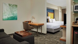Een hotelkamer met een bed, bureau, stoel, televisie en magnetron.