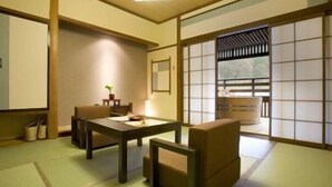 A traditional Japanese room with tatami flooring, a low table, and a cushioned seating area. - Kaidou Roman Onyado Tsutaya (Kiso)