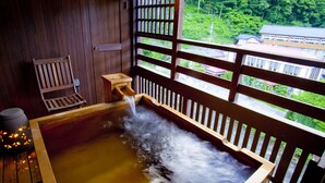 A traditional Japanese onsen with a wooden bench and a small table, a wooden railing, and a view of a building and greenery outside. - Kaidou Roman Onyado Tsutaya (Kiso)